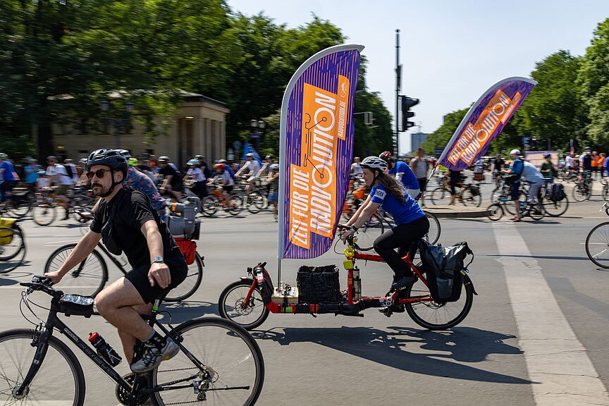 ADFC-Sternfahrt Berlin 2023 Viele Menschen auf Fahrrädern. An einem Rad befindet sich eine große Fahne mit dem Wort "Radvolution" darauf.